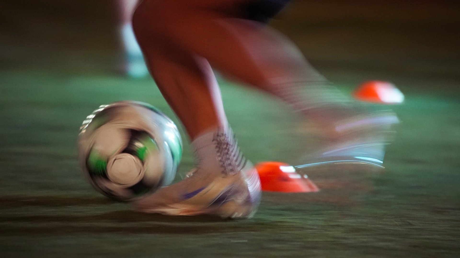 Soccer player in red and white jersey kicking a soccer ball on green field