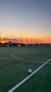 Soccer field at sunset with illuminated floodlights